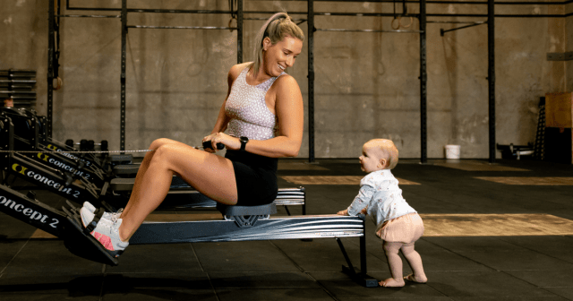 Frau sitzt auf Rudergerät mit Baby 