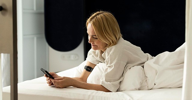 Frau überprüft Schlaftdaten auf Nukkuaa App - ausreichender Schlaf